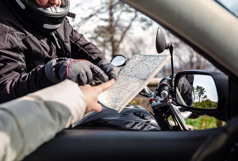 Motorcyclist asking car driver for directions
